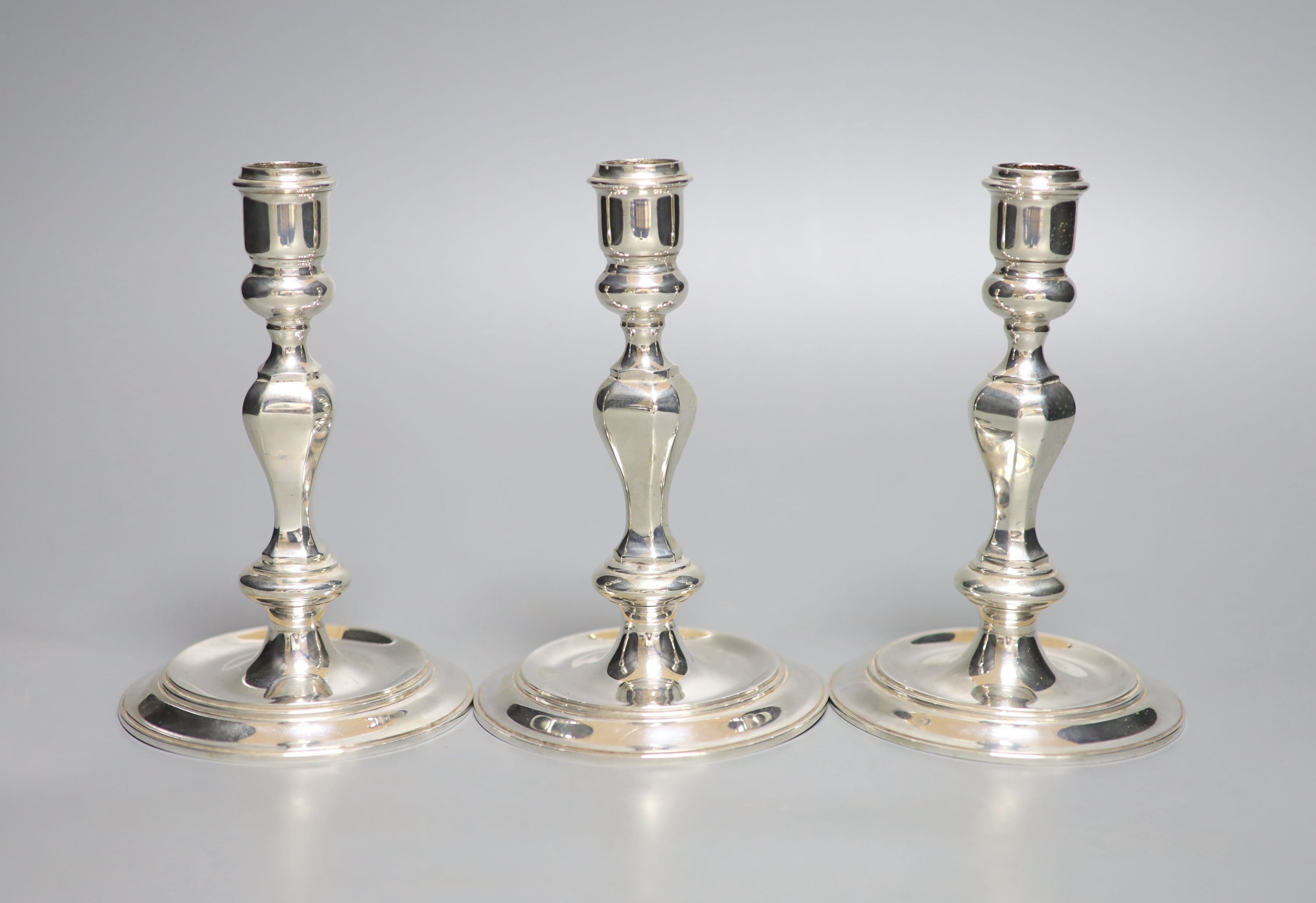 A modern set of three 18th century style cast silver candlesticks, J.B. Chatterley & Sons, Birmingham, 1987, 14.5cm, 24oz.